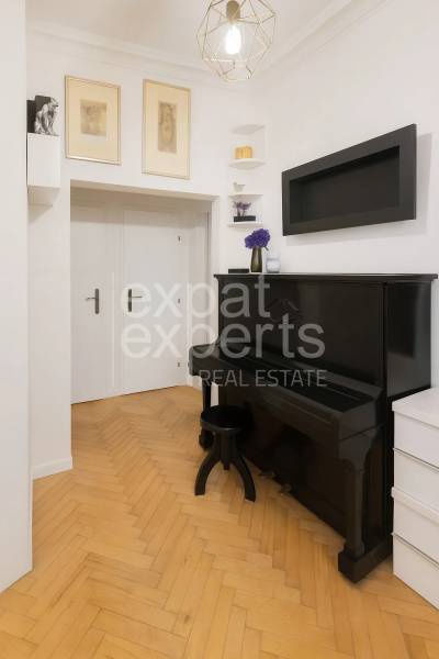 Egy 3 szobás lakás belseje antik fekete zongorával és fa dekorációjú padlóval.