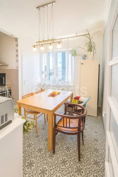 Ebédlő egy háromszobás lakásban faasztallal, székekkel és dekoratív padlóval.