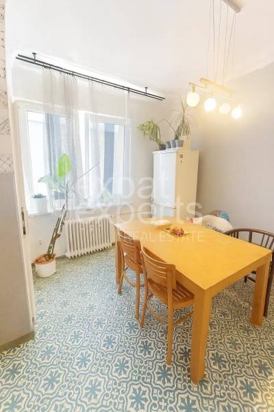 Étkező sarok egy háromszobás lakásban, fa asztallal és mintás padlóval.