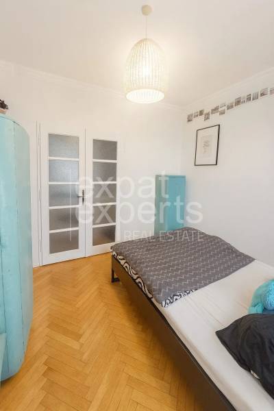 Hálószoba egy háromszobás lakásban, fa mintázatú padlóval és világos ajtókkal.