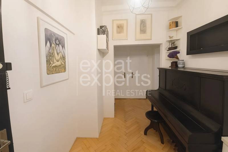 Folyosó zongorával és fa dekorációjú padlóval egy háromszobás lakásban.