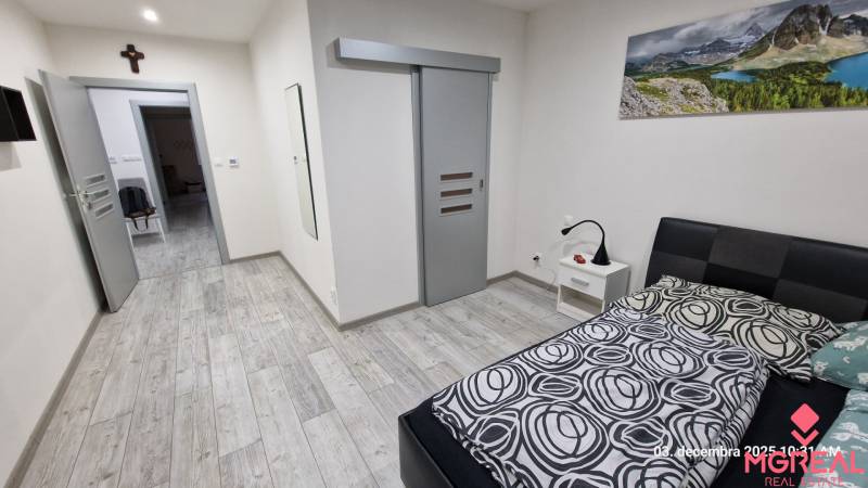 Hálószoba családi házban, fa mintázatú padlóval és tolóajtókkal.