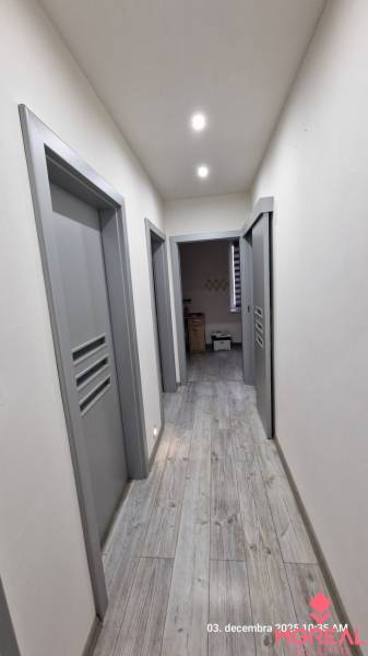 Egy családi ház folyosója fa mintázatú padlóval és szürke ajtókkal.