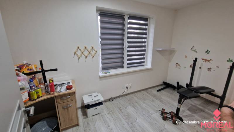 Szoba egy családi házban, fa dekoros padlóval, edzőpaddal és asztallal.