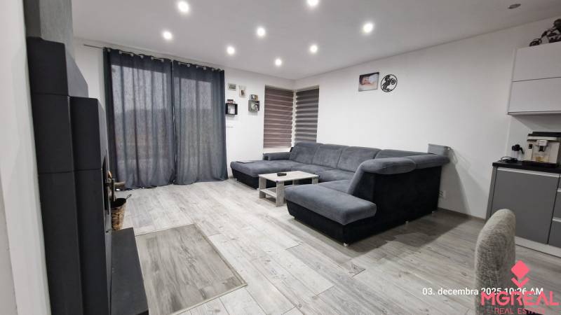 Nappali családi házban kanapéval, asztallal és fa dekorációjú padlóval.