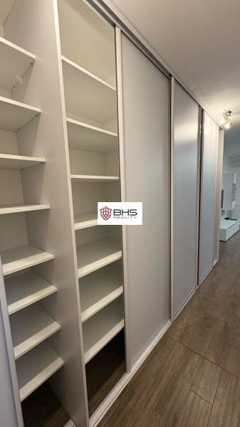 Beépített szekrény egy egyszobás lakásban tolóajtókkal és fa dekor padlóval.