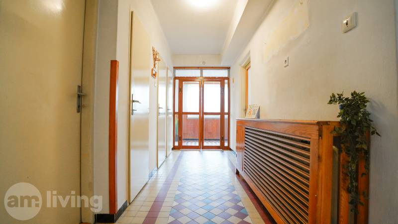 Folyosó egy családi házban csempével és fa radiátorfedéllel.