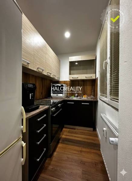 Konyha egy egyszobás lakásban fa dekor padlóval és sötét szekrényekkel.