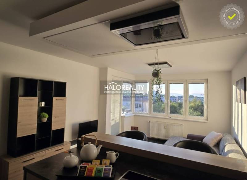 Nappali egy kétszobás lakásban világos falakkal és ablakokkal, bútorokkal berendezve.