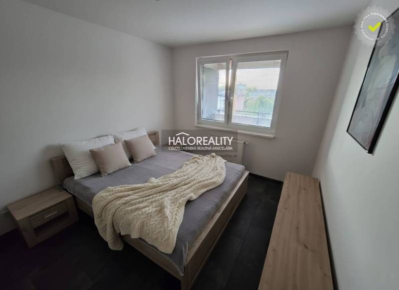 Hálószoba egy kétszobás lakásban ággyal, éjjeliszekrényekkel és faldekorációval.