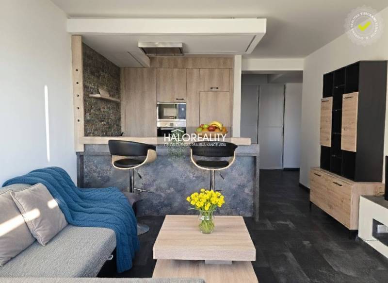 Nappali kétszobás lakásban nyitott konyhával és fa dekoros padlóval.