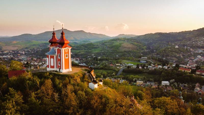 Kálvária a dombon Banská Štiavnica panorámájával, mezőgazdasági és erdészeti területekkel körülvéve.
