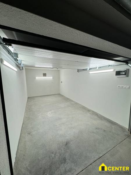 Tágas garázs belső tér betonpadlóval és fehér falakkal.