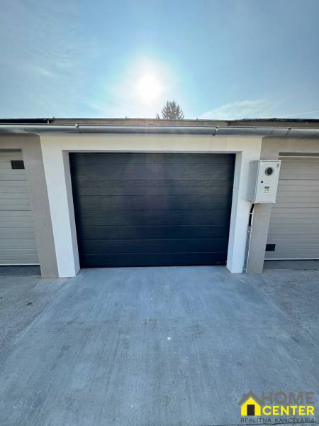 Garázsok a Nap utcában Komáromban sötét kapukkal és betonfelülettel.