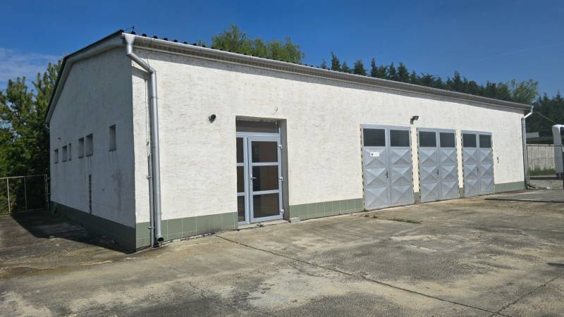 Fehér épület fém ajtókkal a város raktár- és csarnokövezetében, Vágsellyén.