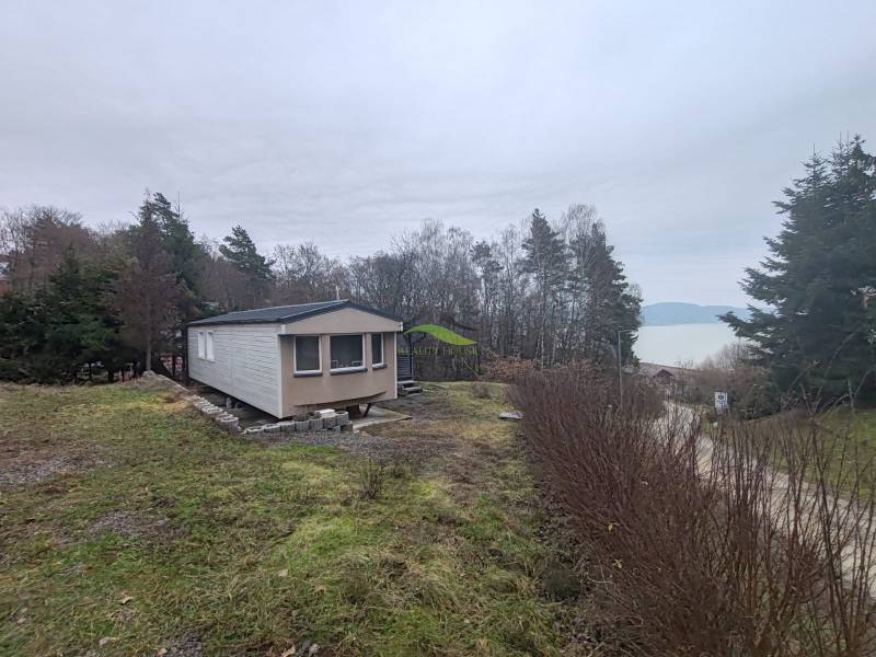 Ház a Fő utcán Újkelcsén, kilátással a vízfelületre és az erdőre.