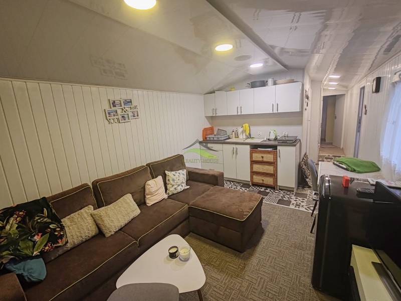 Nappali a házban kényelmes kanapéval, konyhapulttal és dekoratív falburkolattal.