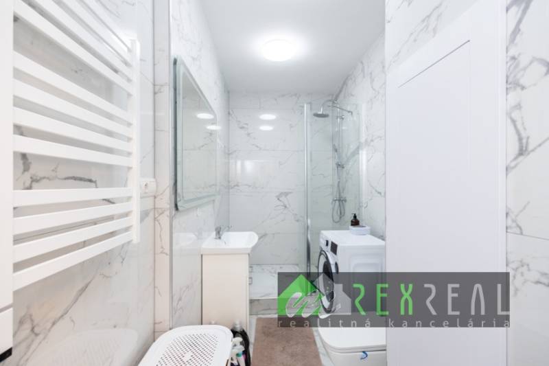 Fürdőszoba zuhanyzóval, mosógéppel és márványfallal egy háromszobás lakásban.