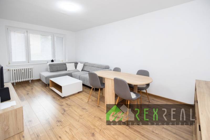 Nappali sarokkanapéval, étkezőasztallal és fa mintázatú padlóval.