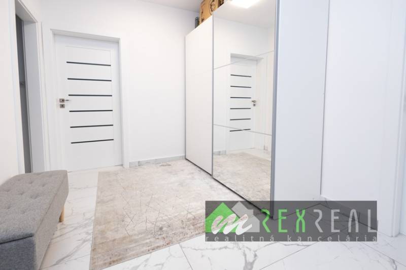 Folyosó szőnyeggel, tükrös szekrénnyel és ajtókkal egy háromszobás lakásban.