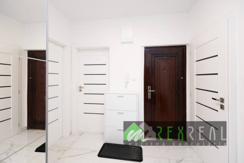 Folyosó fehér ajtókkal és tükrös szekrénnyel egy háromszobás lakásban.