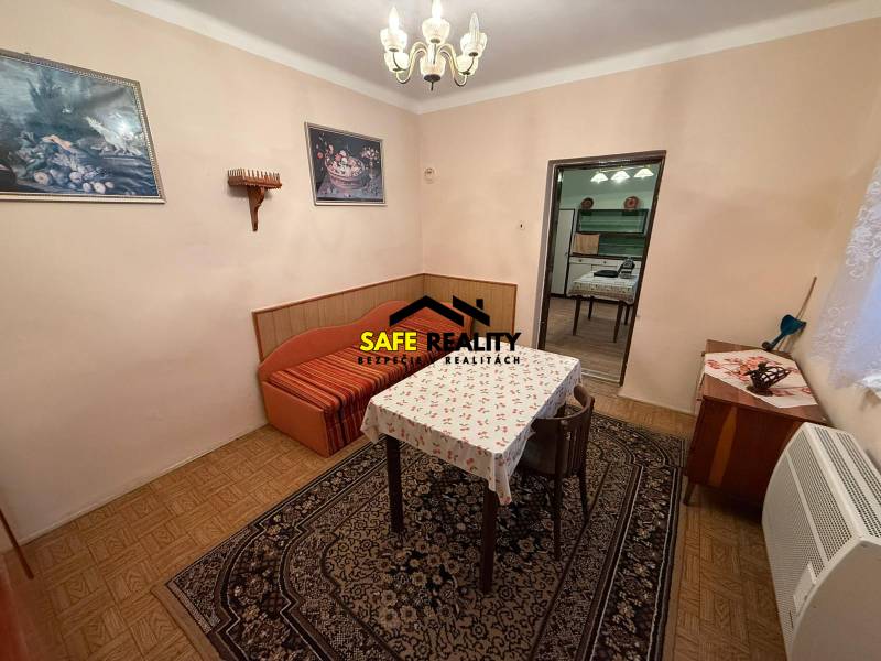 Ebédlő egy családi házban szőnyegekkel, asztallal és székekkel, fa dekorációjú padlóval.