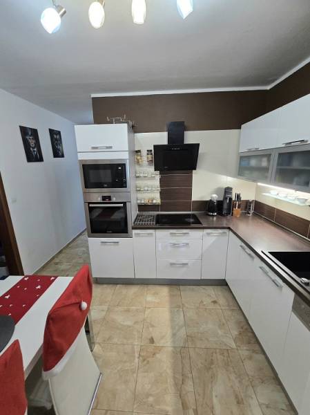 Konyha egy háromszobás lakásban lámpákkal, fehér szekrényekkel és csempével.