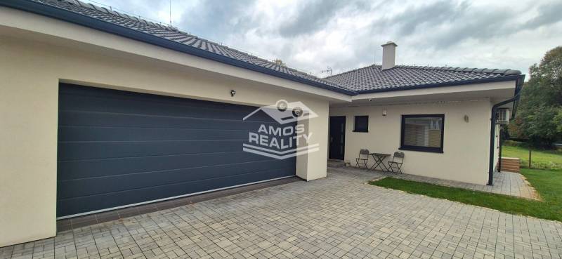 Családi ház Studienkában két székkel és egy asztallal a kövezett udvaron.