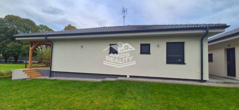 Családi ház Studienkában terasszal, zöld gyepes udvarral és modern homlokzattal.