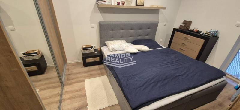 Hálószoba fa dekorációjú padlóval, ággyal és tárolóhelyekkel egy családi házban.