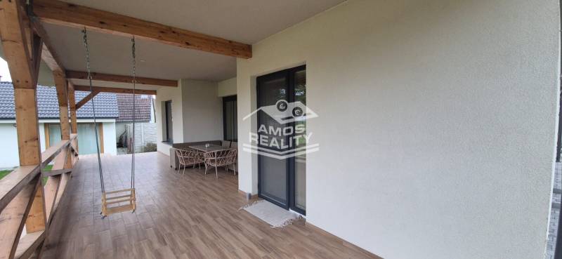 A Studienkában található családi ház terasza hintával és bútorokkal, fa dekorációjú padlóval.