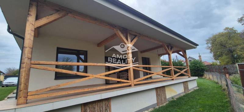 A Studienka-i családi háznak van egy terasza fa korláttal és mellette gyep.