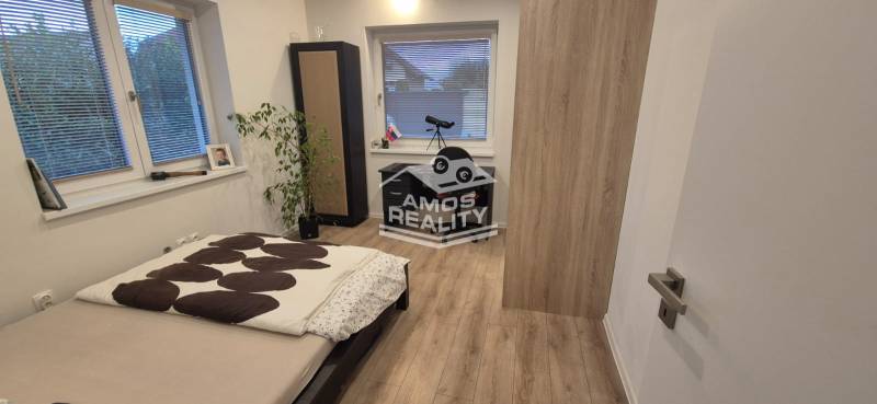 Hálószoba ággyal, asztallal és fa dekorációjú padlóval egy családi házban.