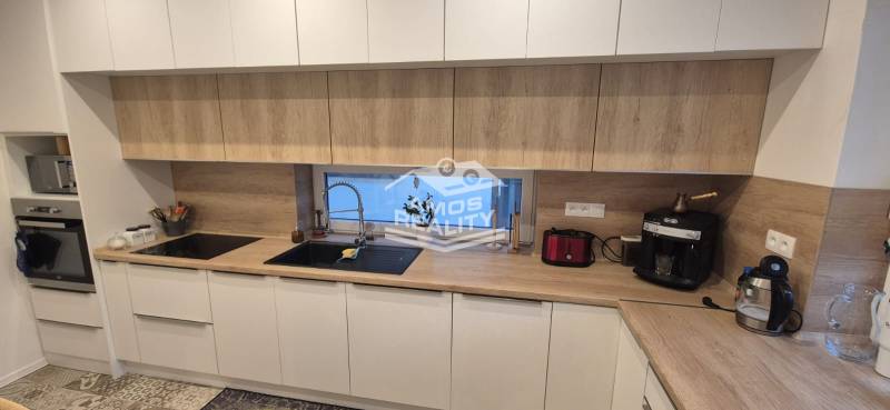 Konyha családi házban fehér szekrényekkel és fa dekoros munkalappal.