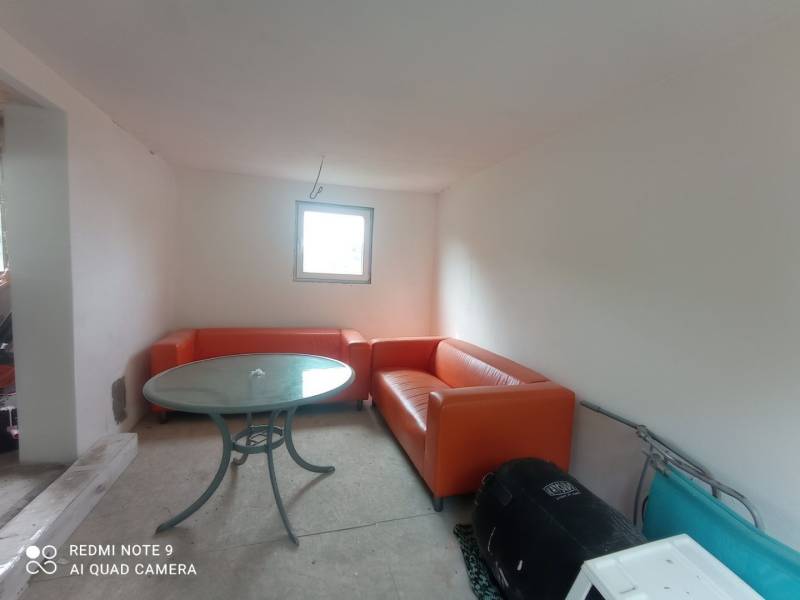 Narancssárga kanapék és kerek asztal egészítik ki a fehér falú ház belső terét.