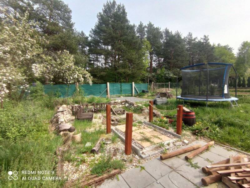 Kert a háznál Hliník nad Hronom-ban trambulinnal és fa járdával.