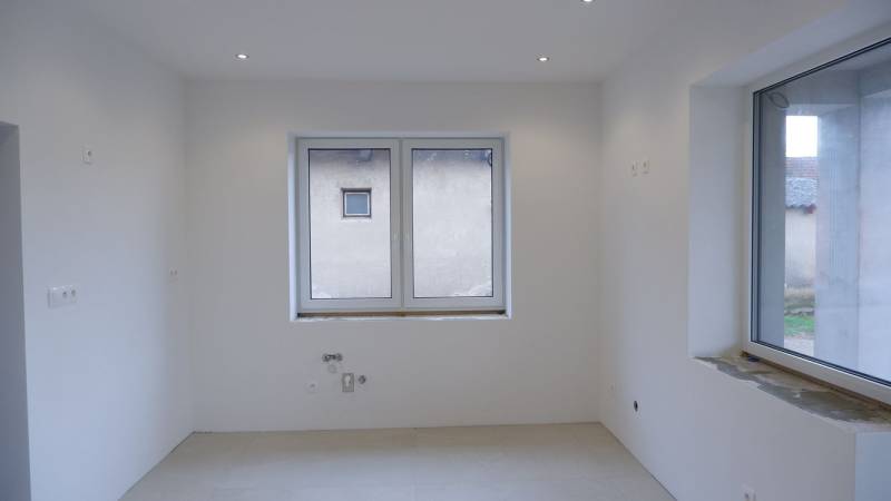 Üres szoba fehér falakkal és nagy ablakkal egy családi házban.