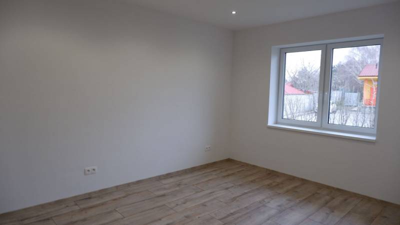 Szoba családi házban fehér falakkal és fa dekorációjú padlóval.