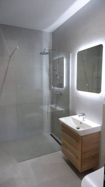 Fürdőszoba mosdóval, zuhanyzóval és nagy tükörrel egy családi házban.