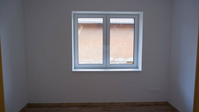 Szoba egy családi házban nagy ablakkal és fa dekorációjú padlóval.