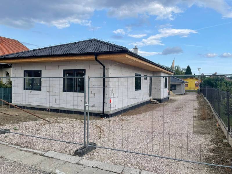 Radaván éppen épül egy családi ház ferde tetővel és fehér homlokzattal.