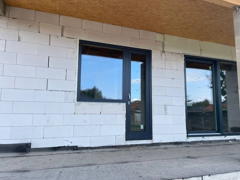 Befejezetlen családi ház homlokzata Radaván műanyag ajtókkal és ablakokkal.