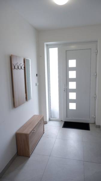 Családi ház előszobája fogassal, tükörrel és dizájnos ajtókkal.