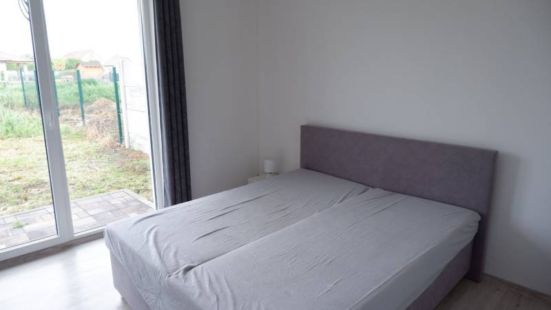 Hálószoba családi házban ággyal és padlóig érő nagy ablakokkal, fa dekorációval.