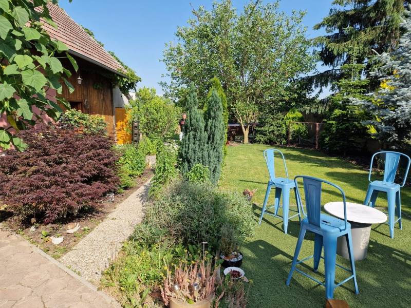 Egy családi ház kertje Dlhá nad Váhom-ban, faházzal és kék székekkel.