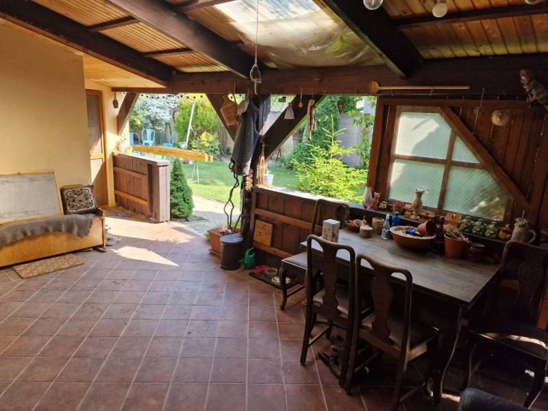 Családi ház rusztikus terasza fa bútorokkal és kilátással a kertre.