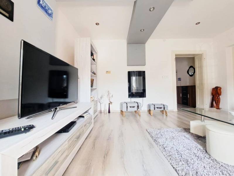 Nappali egy családi házban, televízióval és fa dekorációjú padlóval.