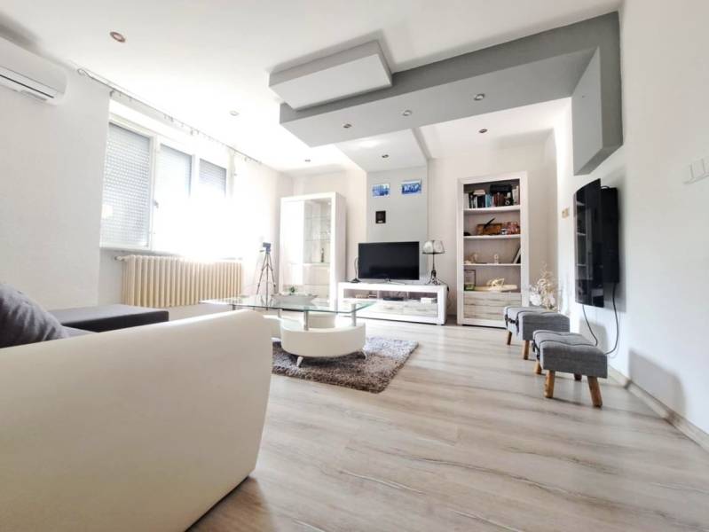 Nappali egy családi házban fa dekor padlóval és kanapéval.