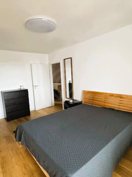 Hálószoba családi házban ággyal, komóddal és fa dekorációjú padlóval.