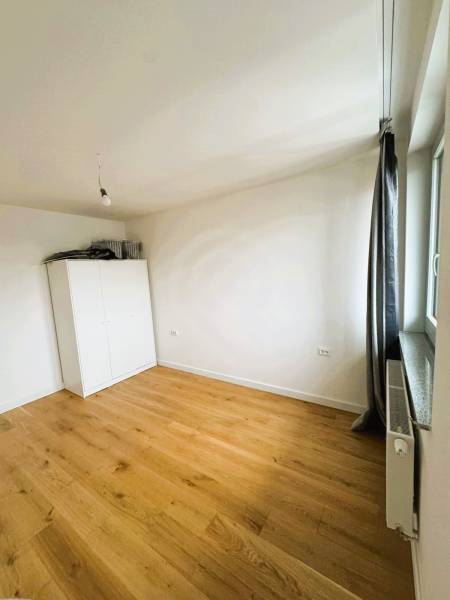 Szoba egy családi házban fehér szekrénnyel és fa dekorációjú padlóval.